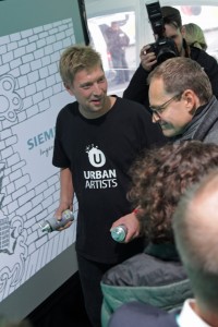 Berlins Bürgermeister Müller besucht die Digitale Graffiti Wand.